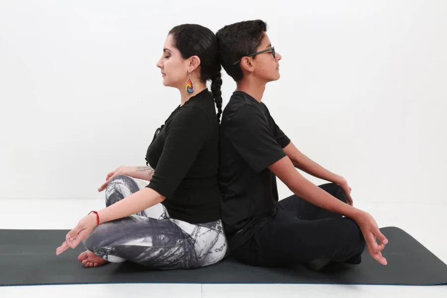 Dos personas meditando espalda con espalda sobre un mat de yoga