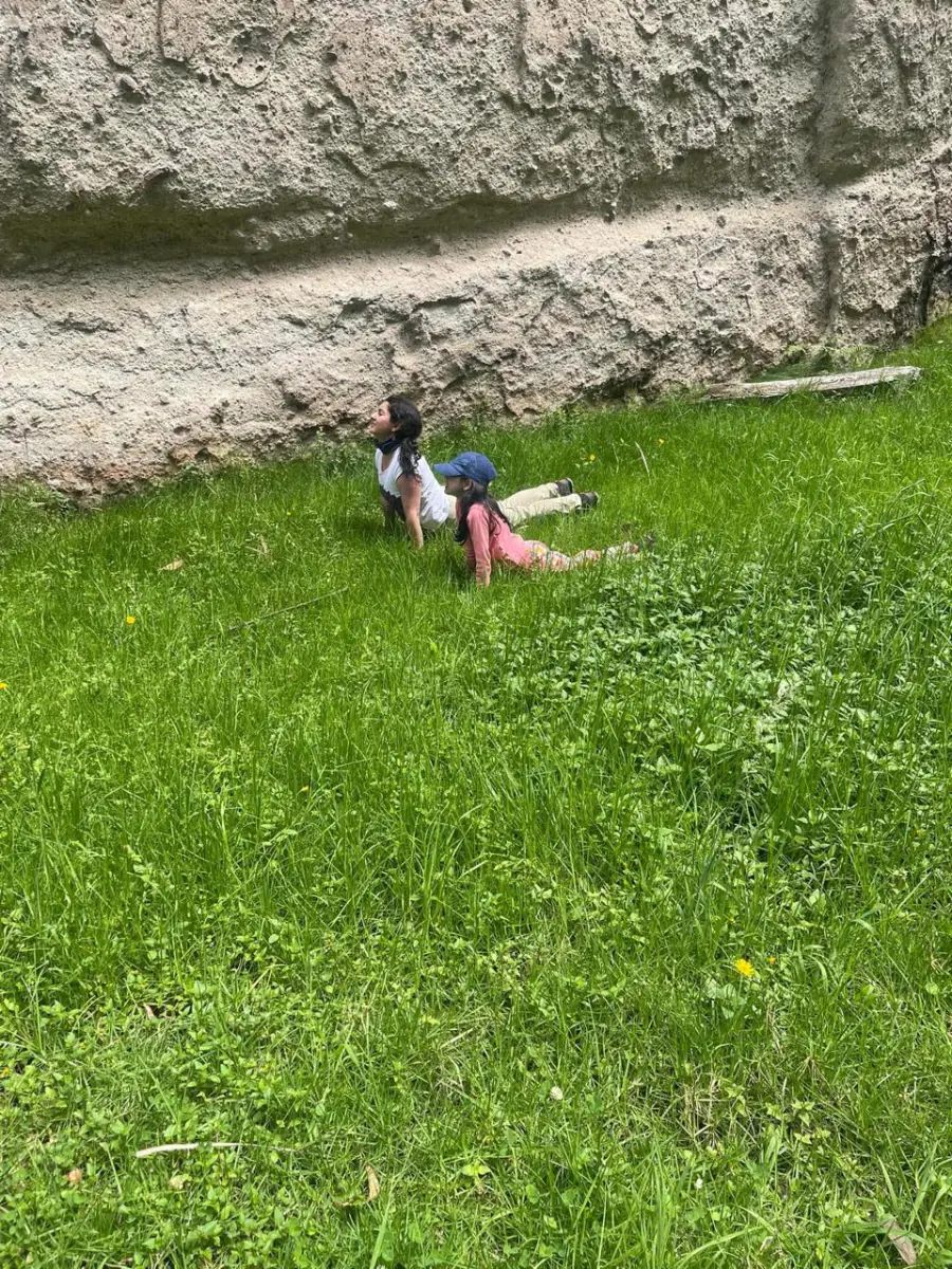 Gabriela practicando yoga en el pasto junto a su hija