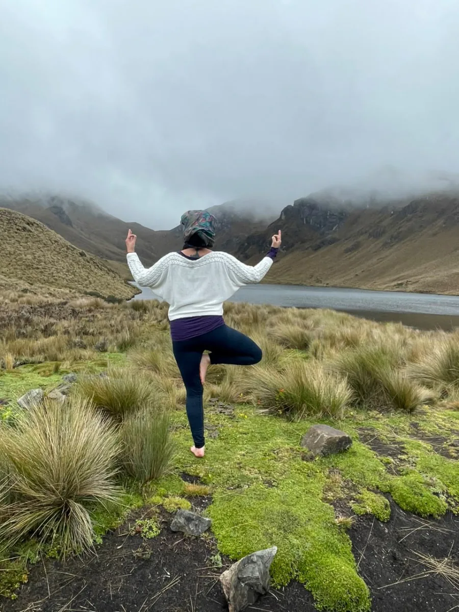 Mujer practicando yoga en postura del árbol frente a una laguna de páramo